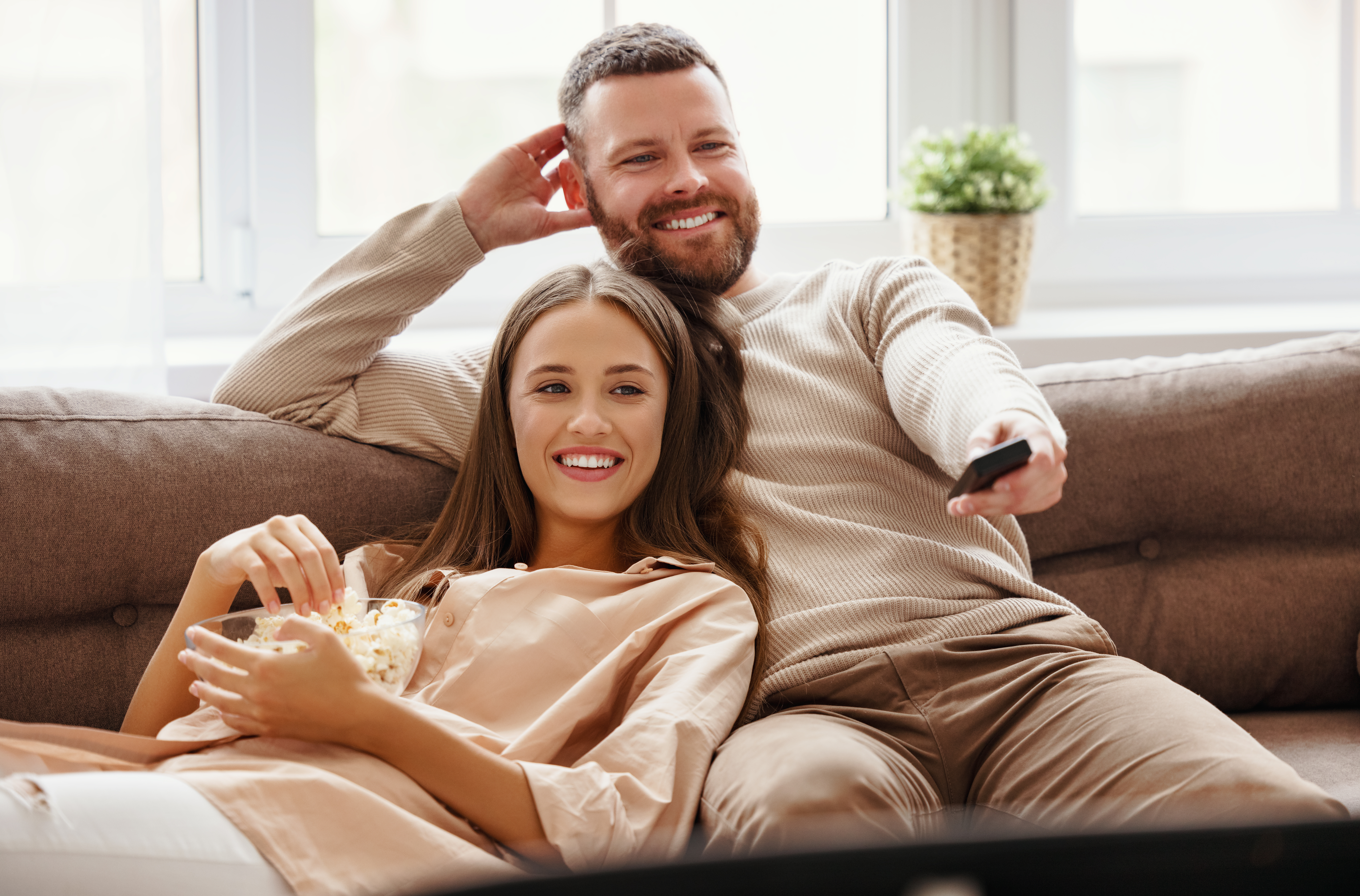 Happy family couple watching television at home on the sofa